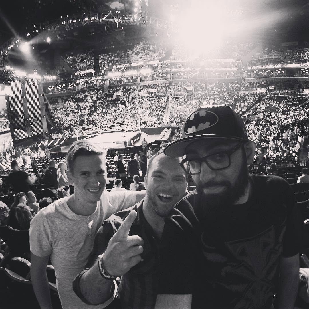 Devon and two friends taking a selfie in a packed arena, in black and white